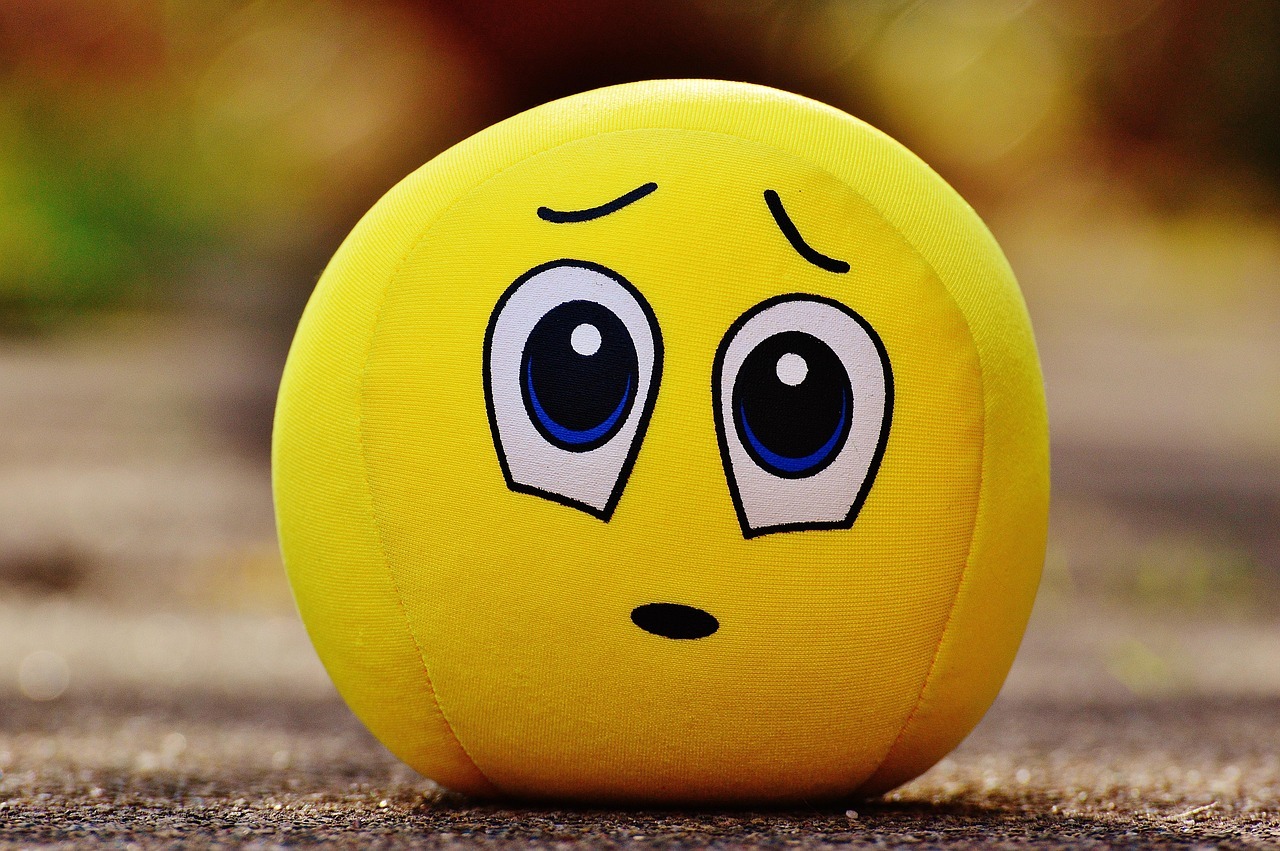 A yellow squeeze ball in the style of an emoji with an anxious face.